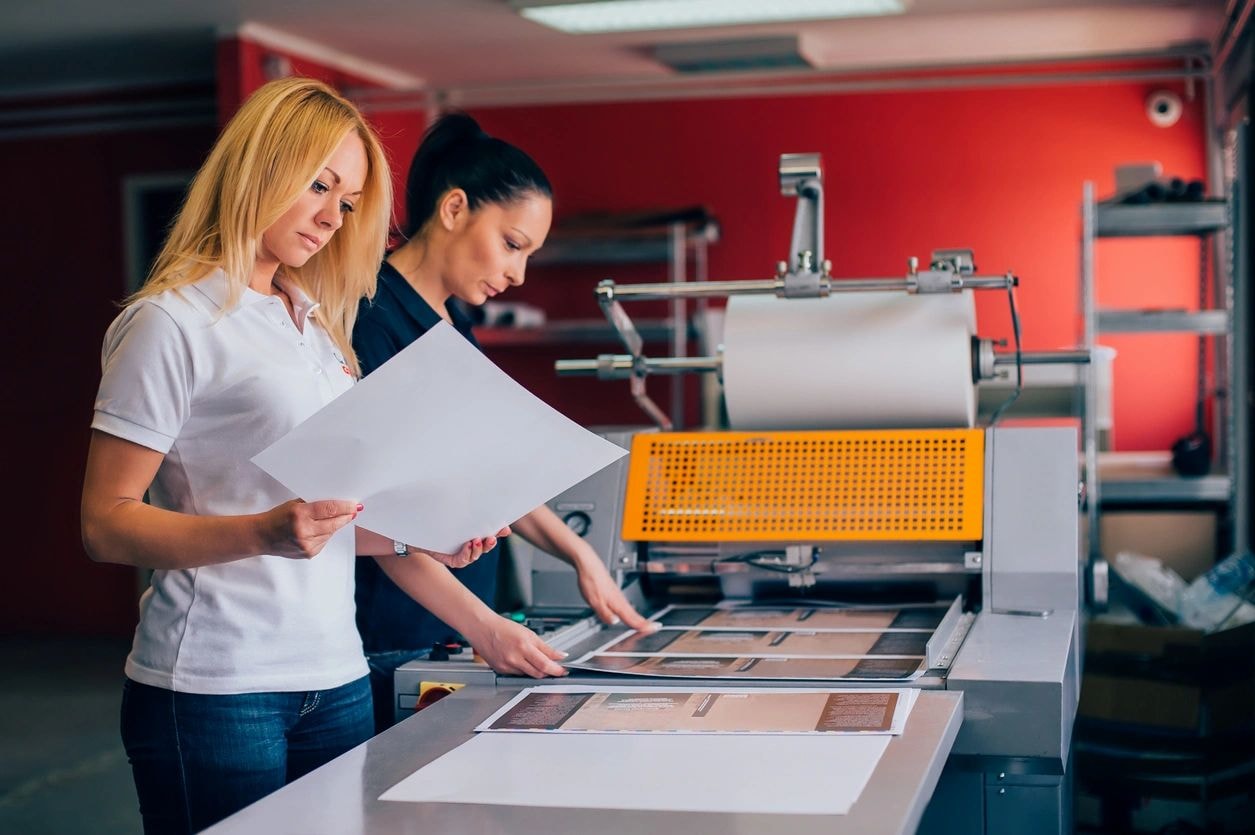 Two women examining printed materials in a printing facility
